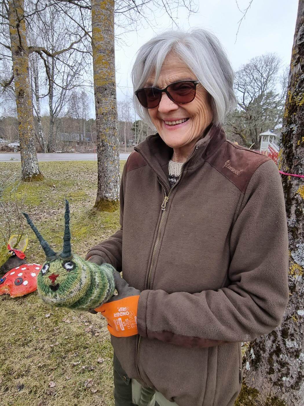 Kvinna som håller i en stickad larv utomhus.