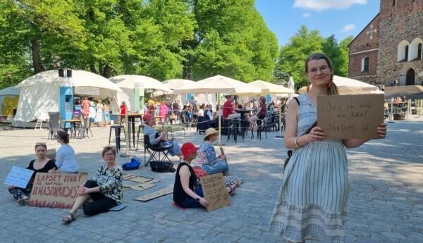 liten protest på ett torg med en uteservering i bakgrunden