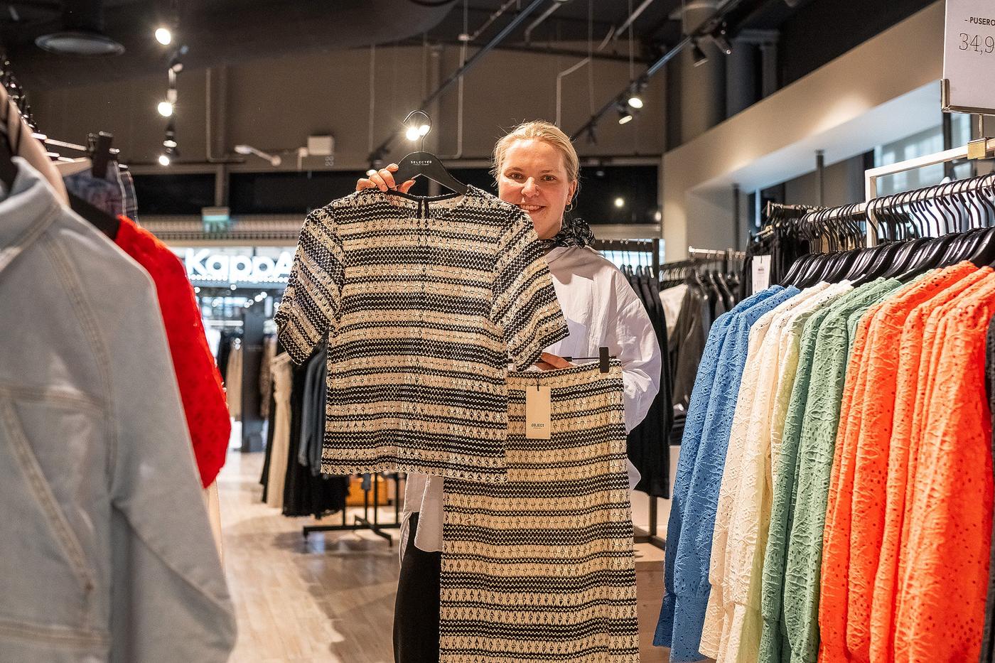 en kvinna håller upp en klänning och en blus