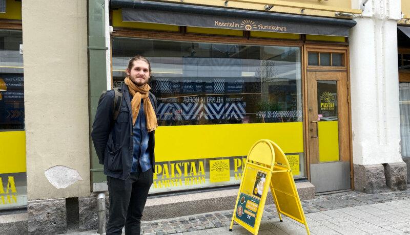 Man som står på gatan framför ett café.