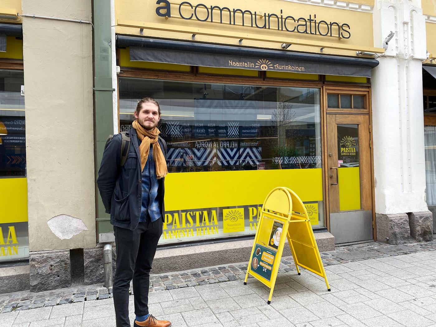 Man som står på gatan framför ett café.