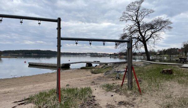 En sandstrand med brygga och gungställningar