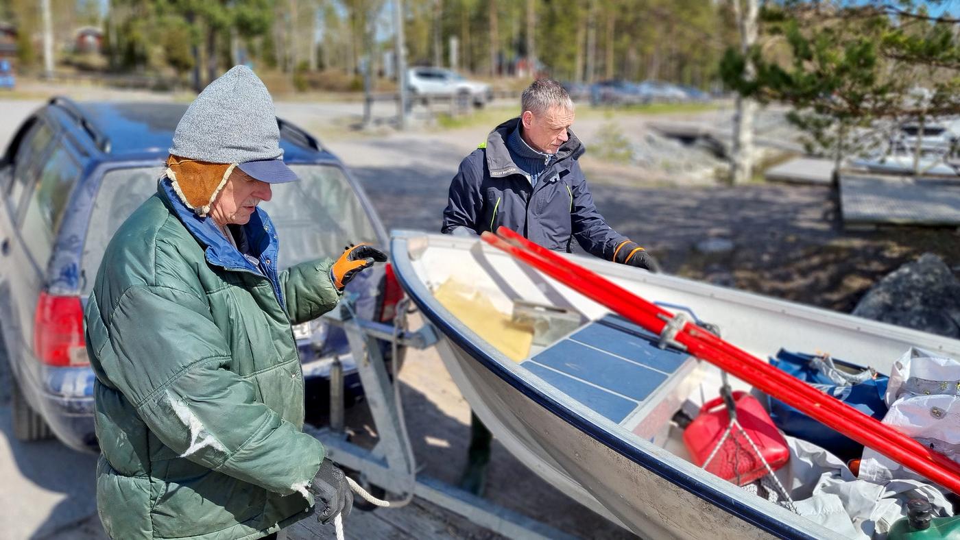 Två män sjösätter liten båt.