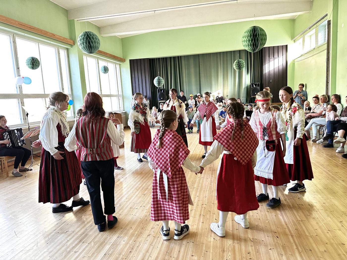 Unga folkdansare i en ring i en gymnastiksal.