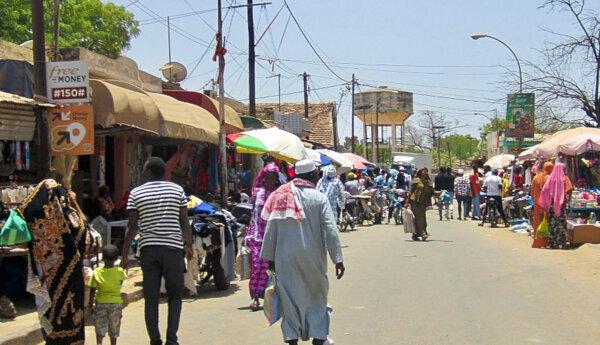 afrikansk marknad med en dammig gulskiftande sandgata i förgrunden