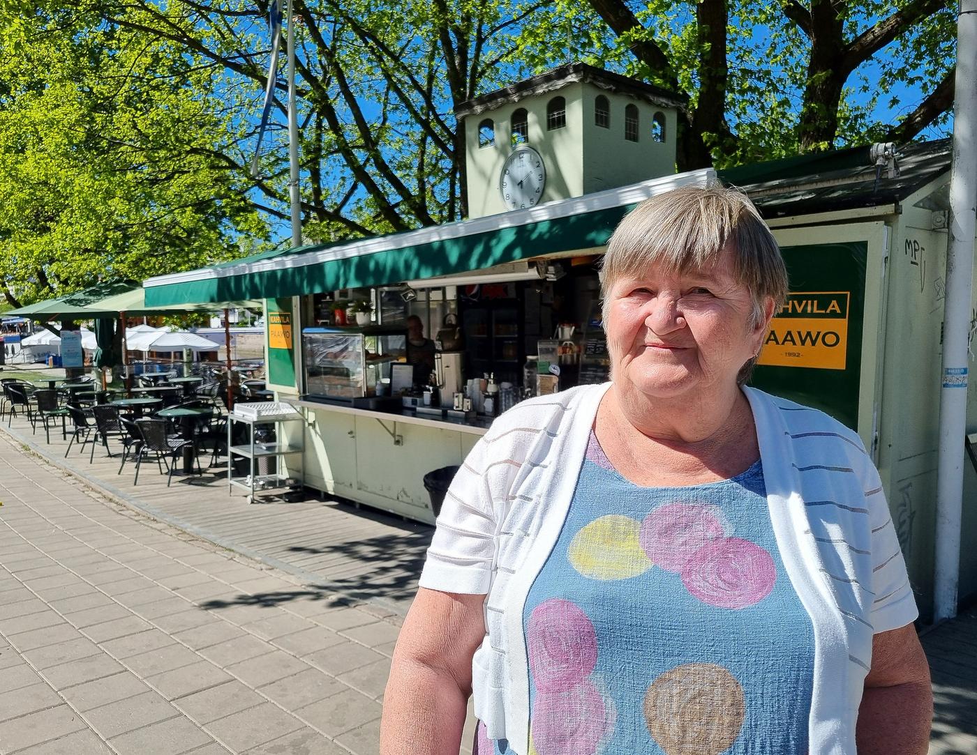 En gråhårig kvinna står utanför ett gatukafé