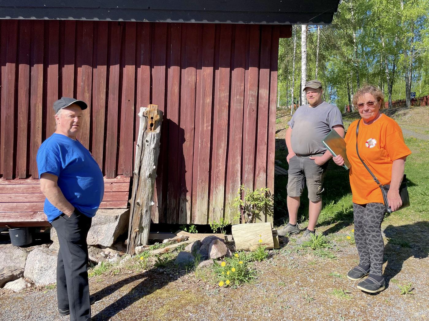 tre personer vid en röd trävägg