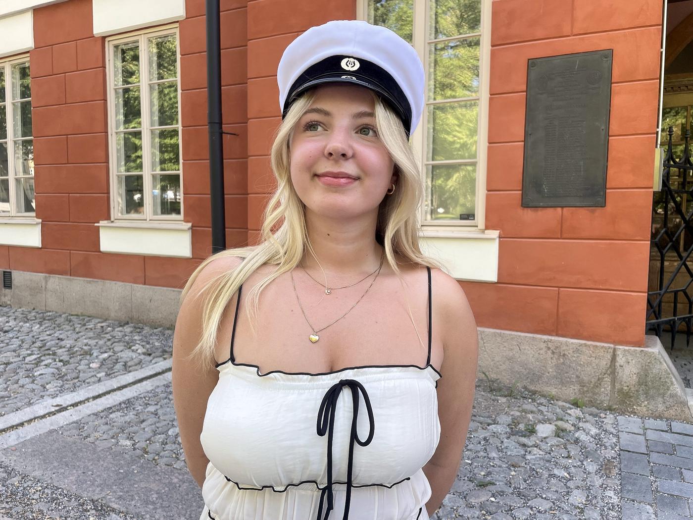 Edith Friis med studentmössan på huvudet framför Katedralskolan i Åbo.