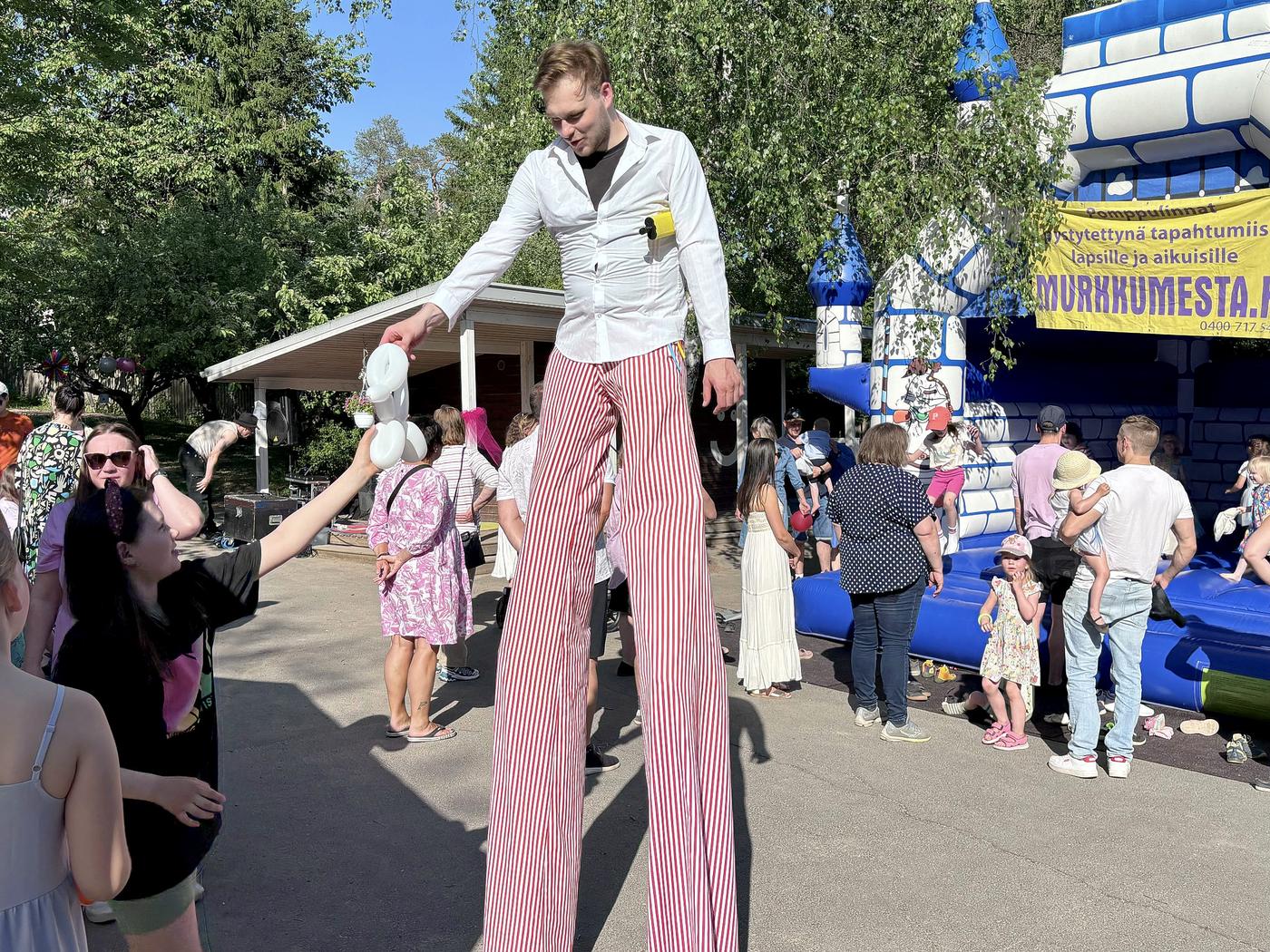 man på styltor delar ut ballonger