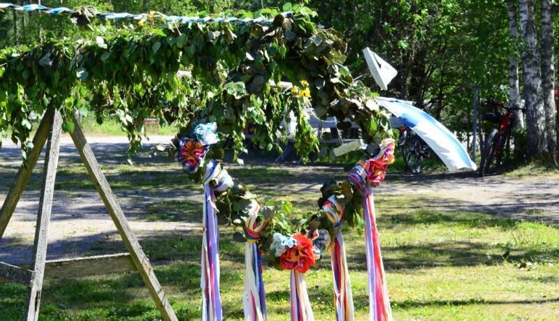 en midsommarstång med en blomsterkrans och den finska flaggan