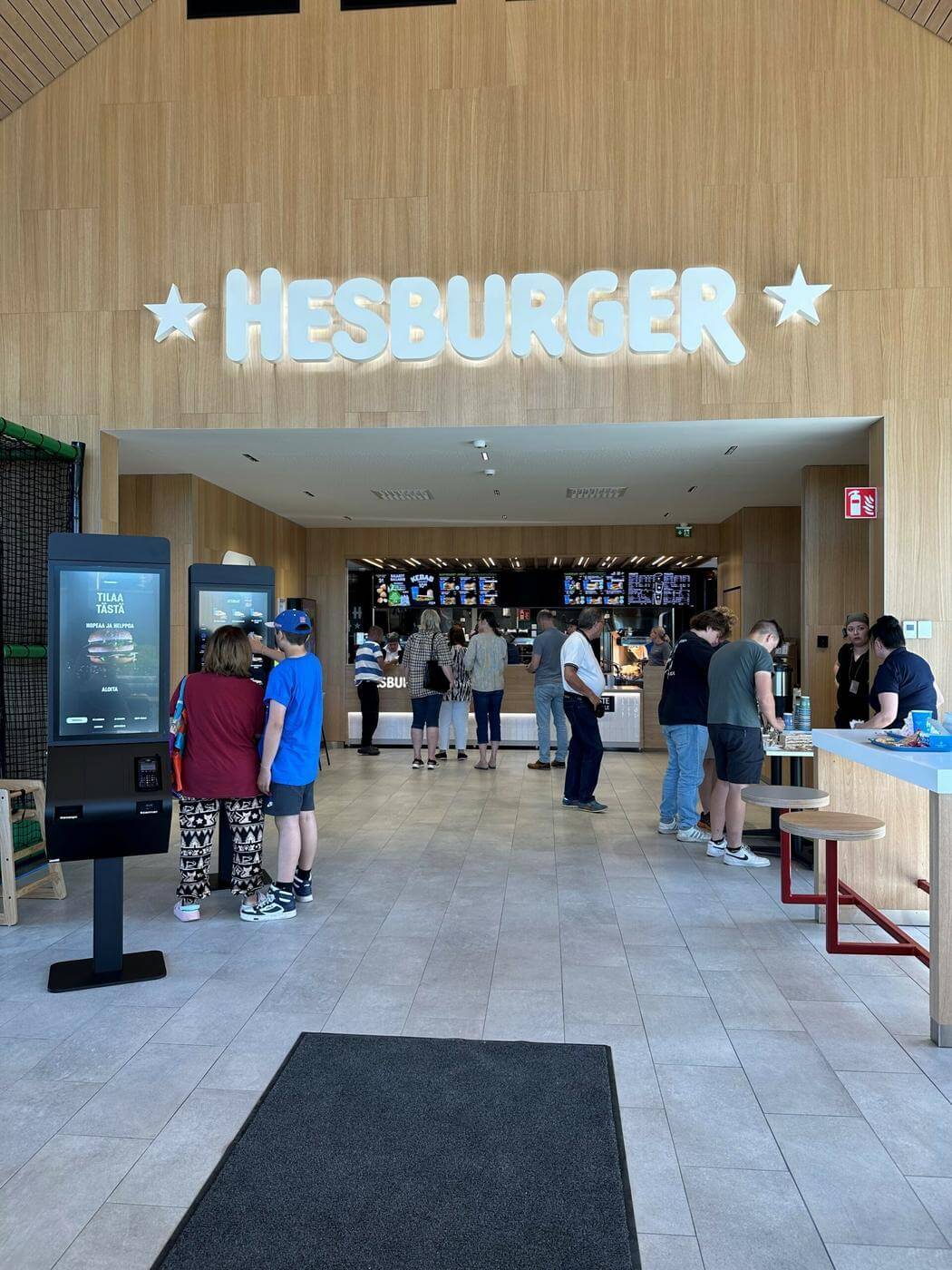 Inne i Hesburger-restaurang, framför finns stor Hesburger-skylt samt kök.