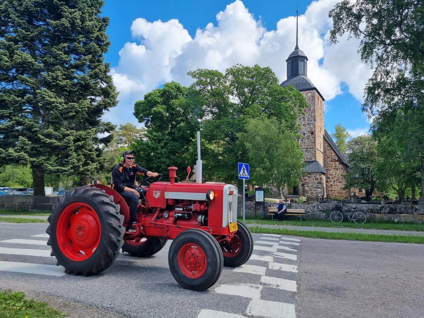 En man på traktor framför kyrka.