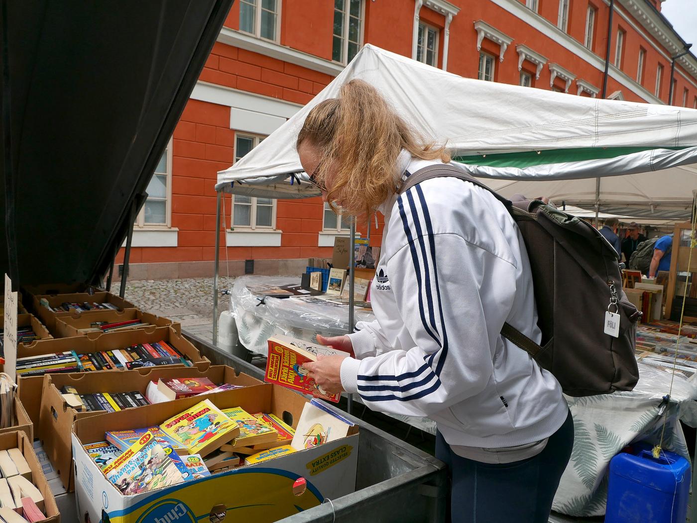 Bild på Lilli Kojo då hon letar efter böcker i en trailer.