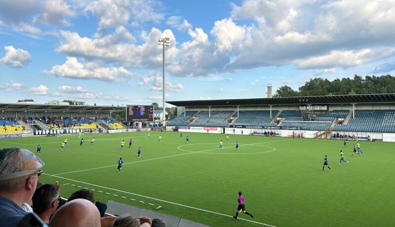 Spelare i gula och mörkblå skjortor på en fotbollsplan