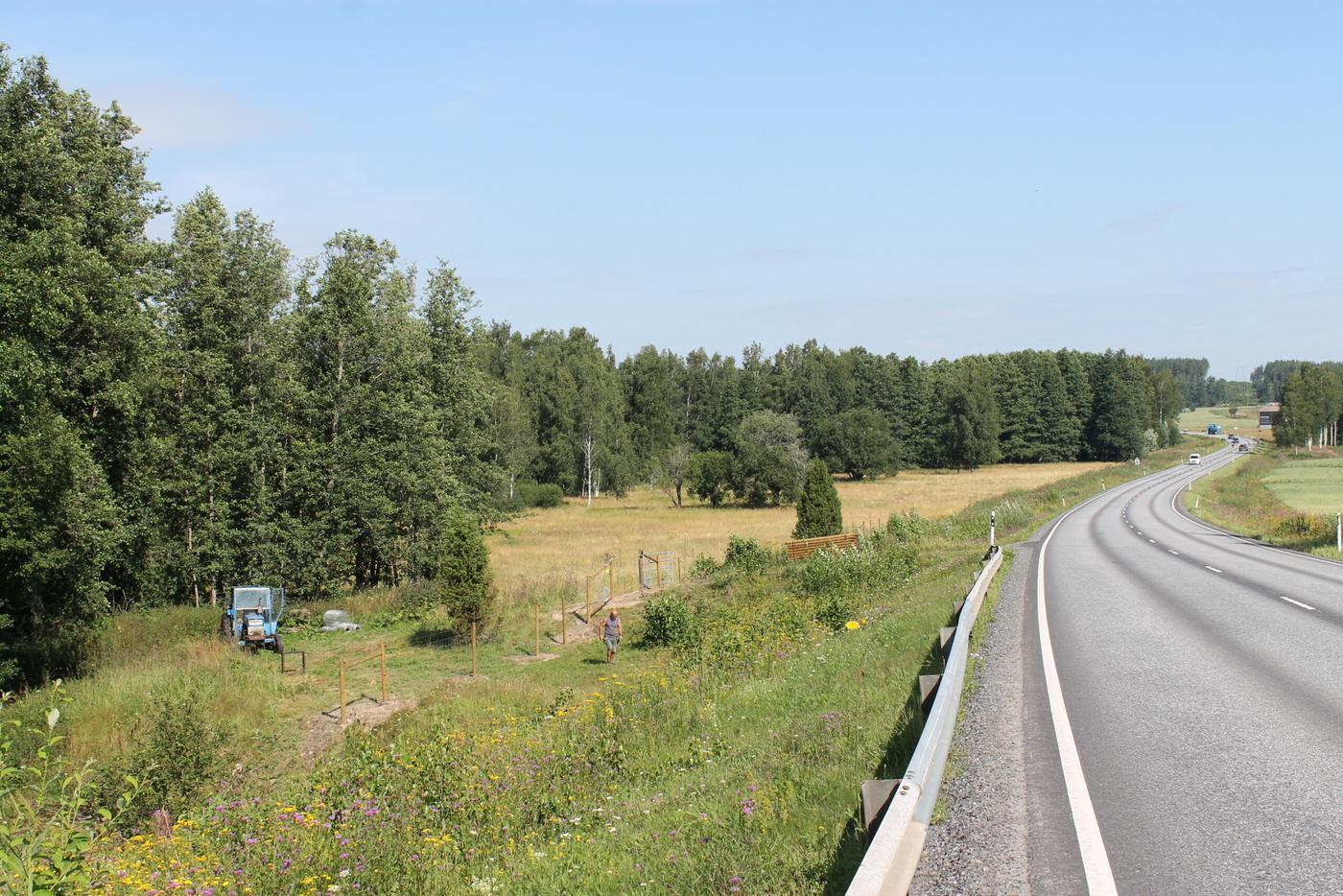 En väg löper längs med en fårhage i Tenala, Gennarby, som står utan får. Solen lyser.