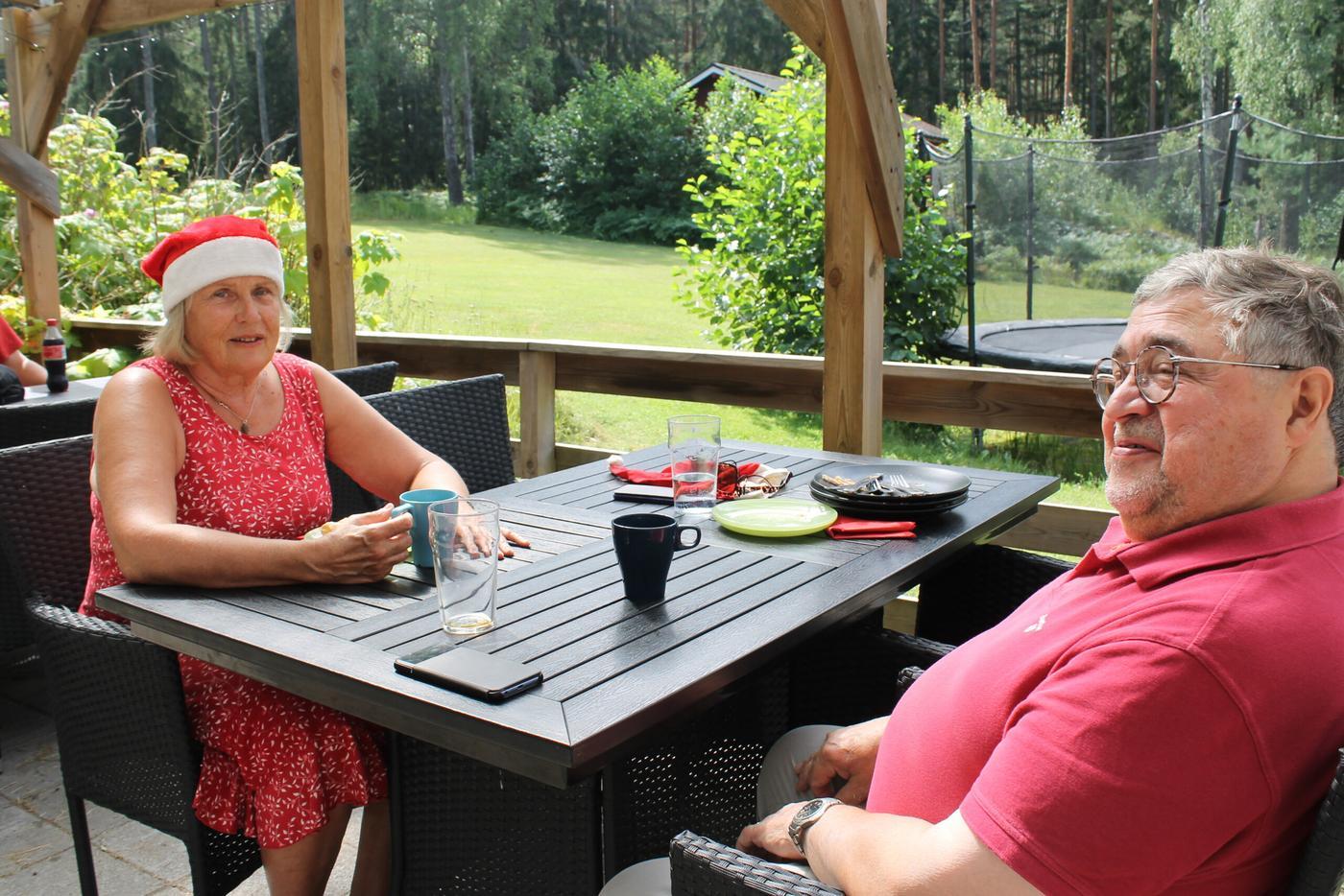 En äldre kvinna och man sitter vid ett bord på restaurangen Skatafé i Bromarv. Skatafé firar jul i juli och därför bär kvinnan på bilden en tomteluva.