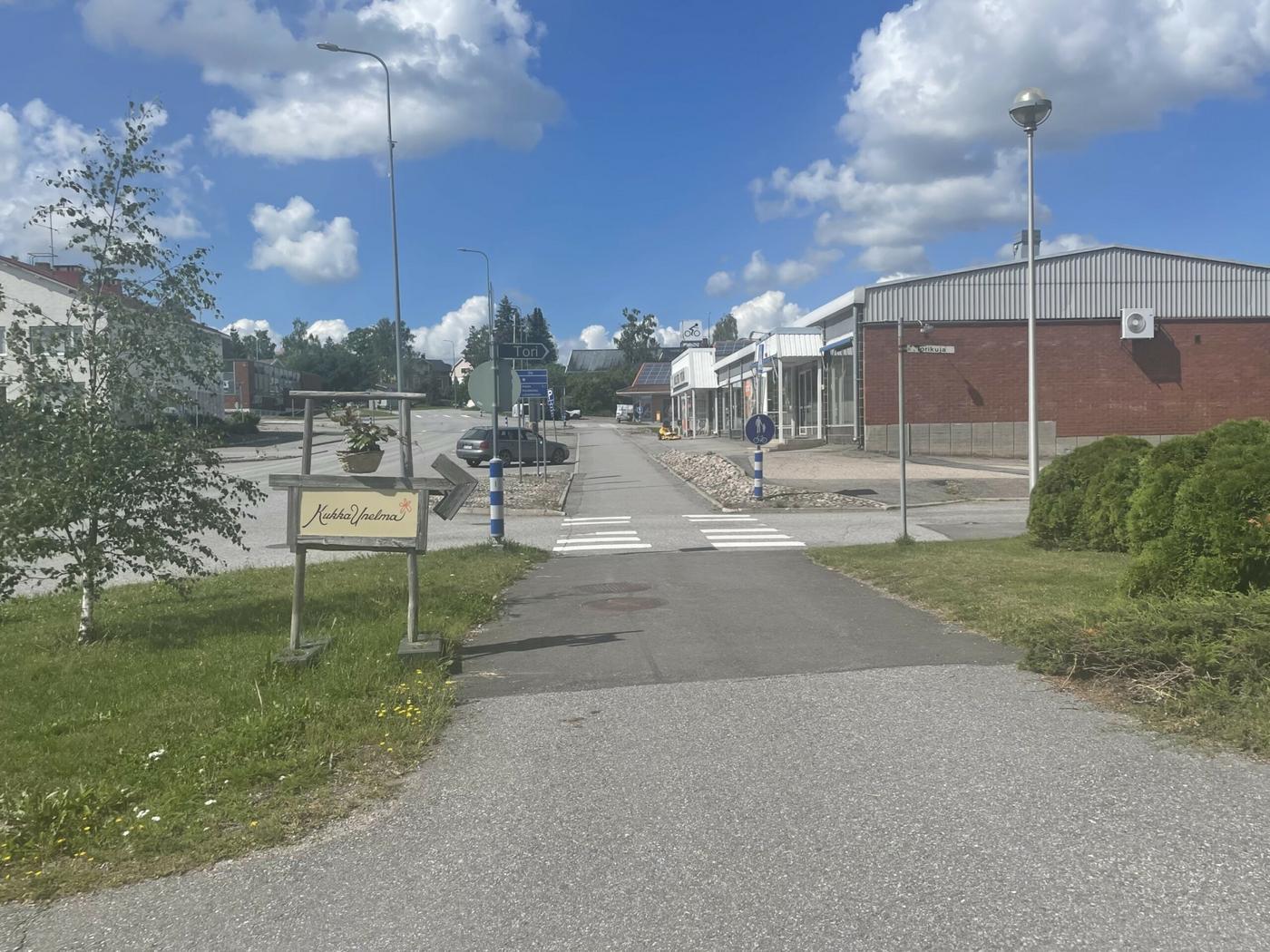 Bild på ett litet centrum med några byggnader, en skylt och ett övergångsställe. 