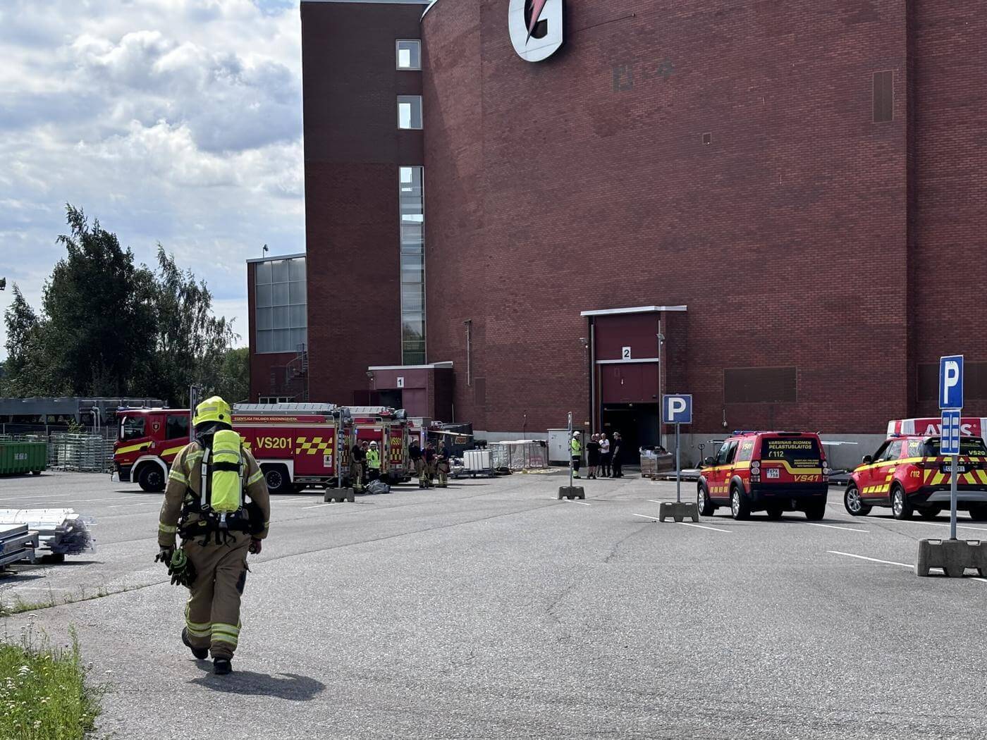 Brandbilar och brandsoldater utanför en hall.