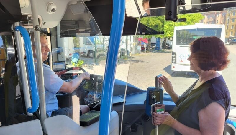 Chaufför och passagerare vid förarhytten på en stadsbuss