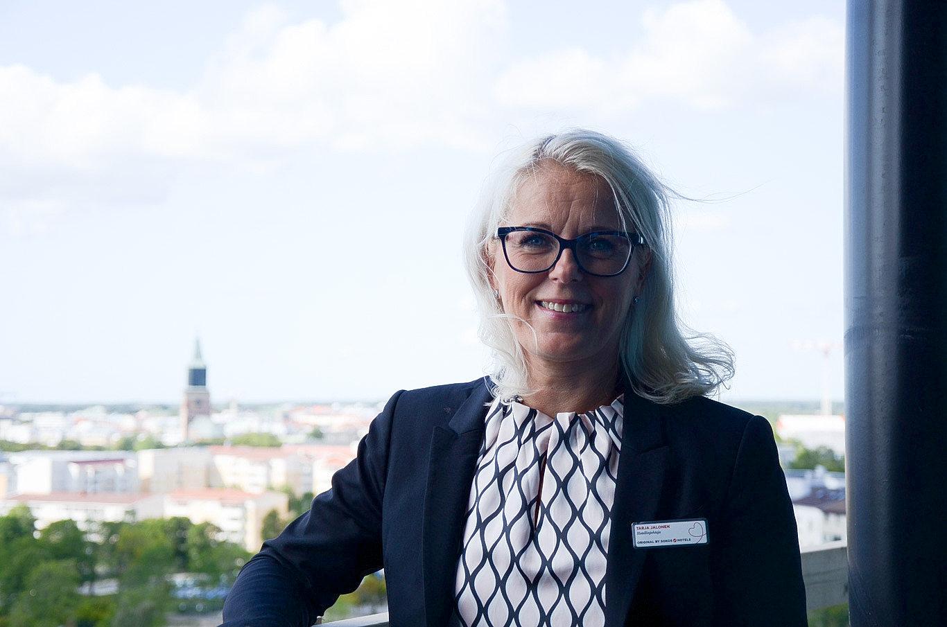 Bild på en ljushårig kvinna med svart kavaj och svartvit blus.