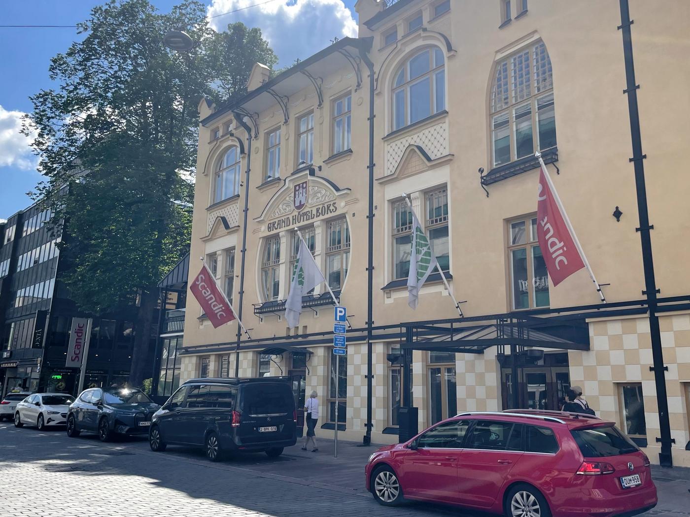 Bil på en lljus hotellbyggnad.