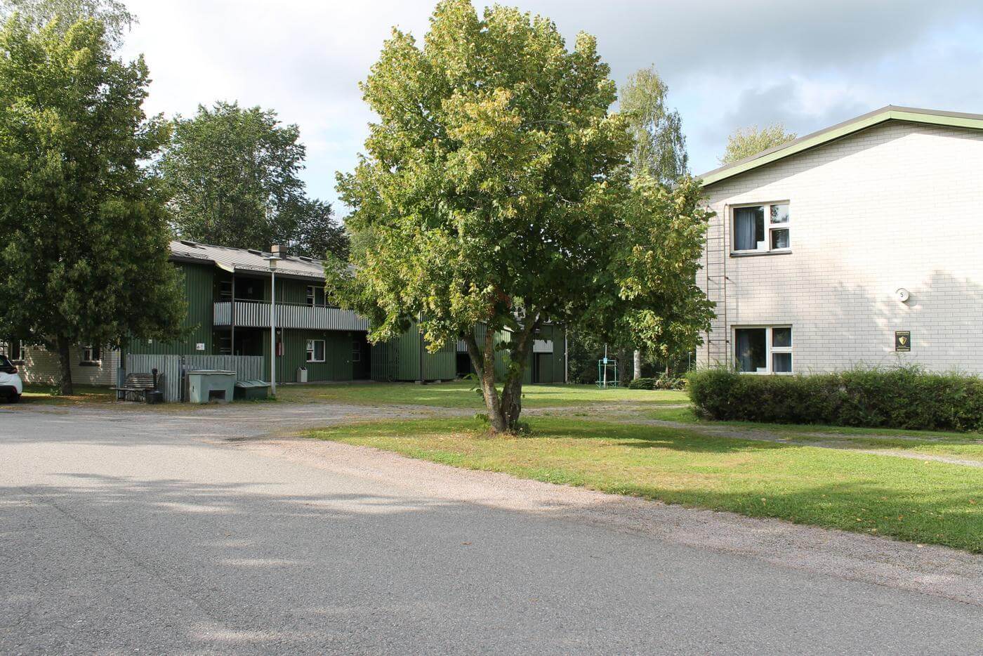 Ett vitt hus syns närmast kameran och i bakgrunden ser man ett grönt trähus. Husen är internat för studernade vid Axxell och Västra Nylands folkhögskola i Karis.