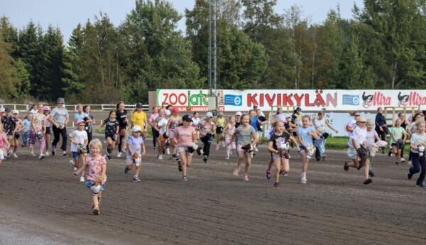 Små barn med käpphästar på travbana